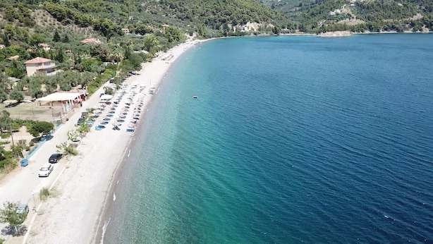 A coastal area with a beach, parked cars, and buildings. - Limni Stone Apartment (Mantoudi-Limni-Agia Anna)