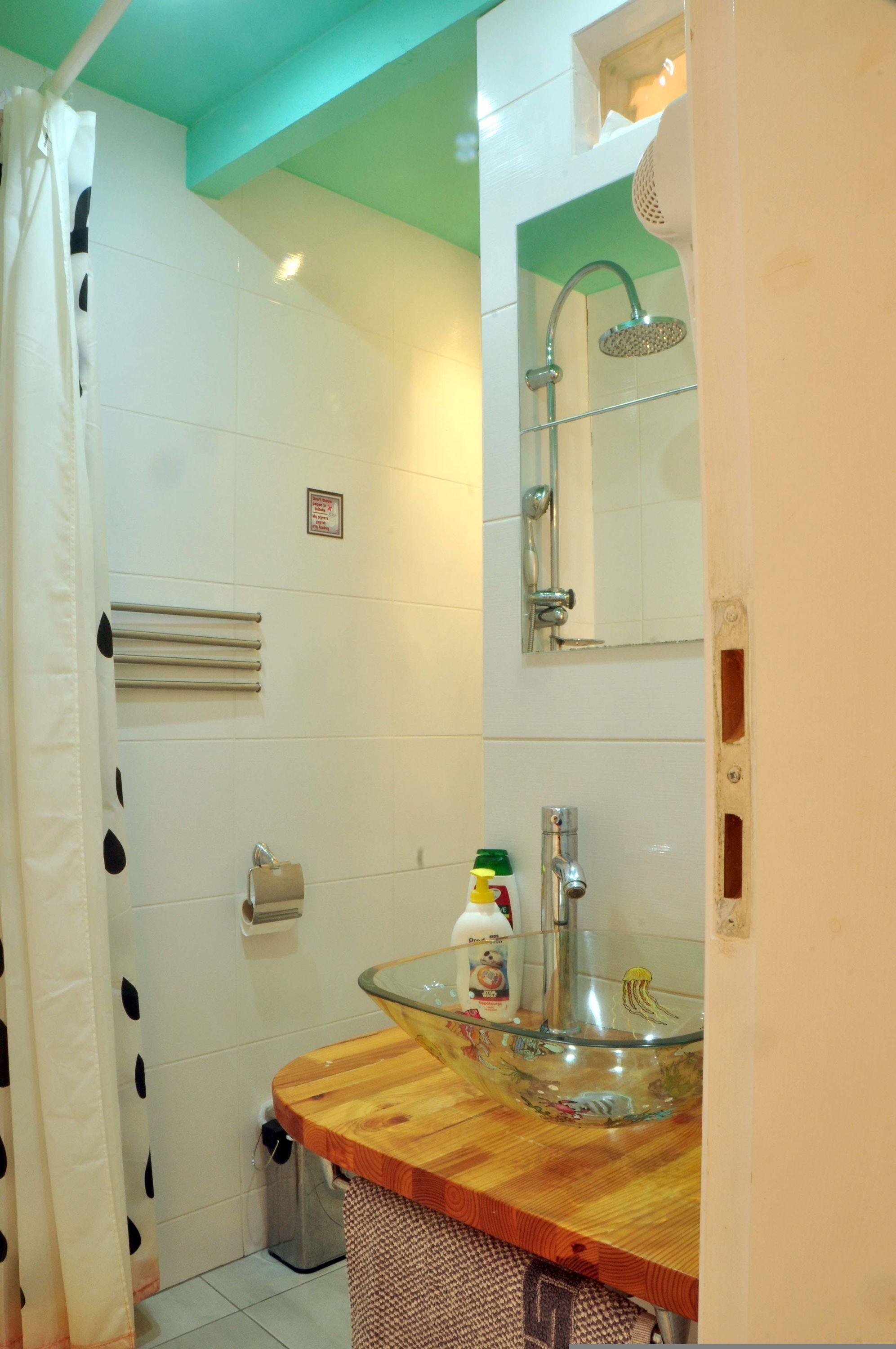 A bathroom with a shower, a glass sink, and a toilet.