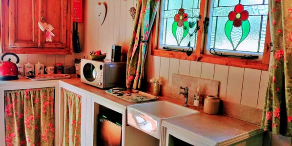 A compact kitchen with a microwave, kettle, and various kitchen items on the counter. - Shepherd's Hut in Romsey With Fire Pit (Romsey)