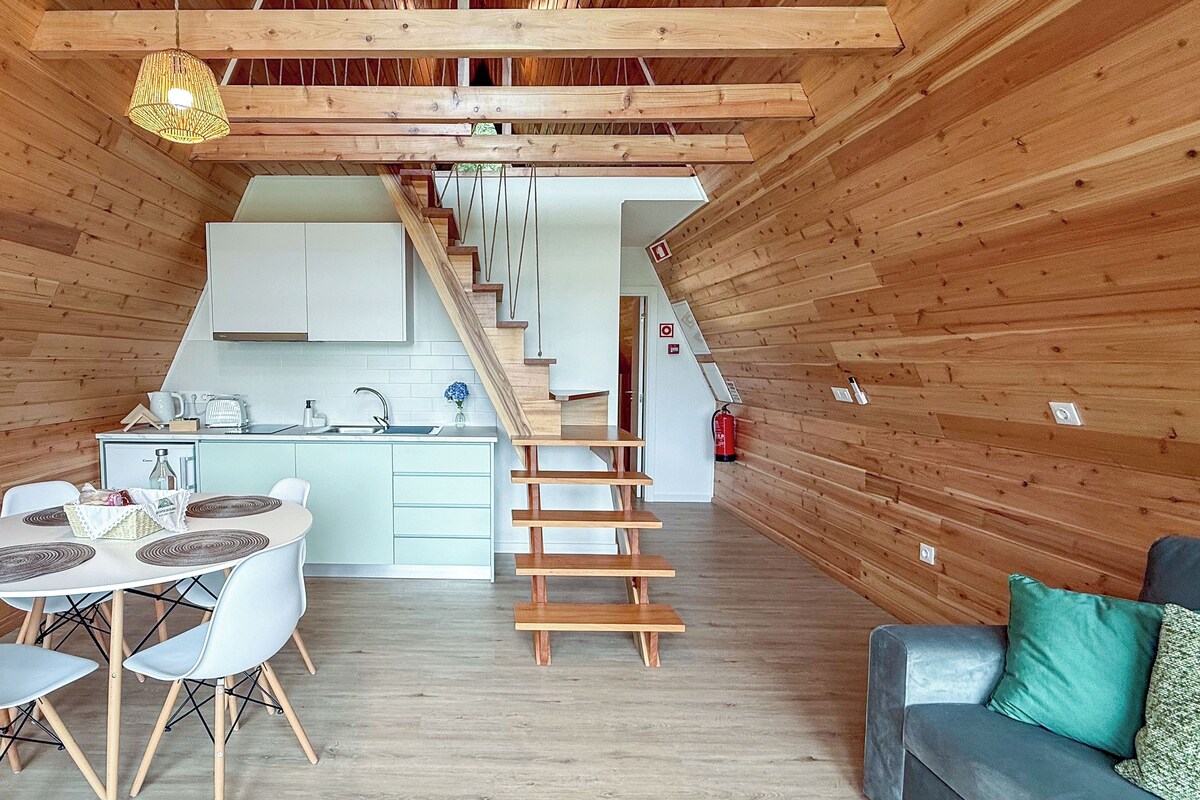 A modern kitchen with white cabinets, a wooden staircase, and a dining area with a table and chairs.