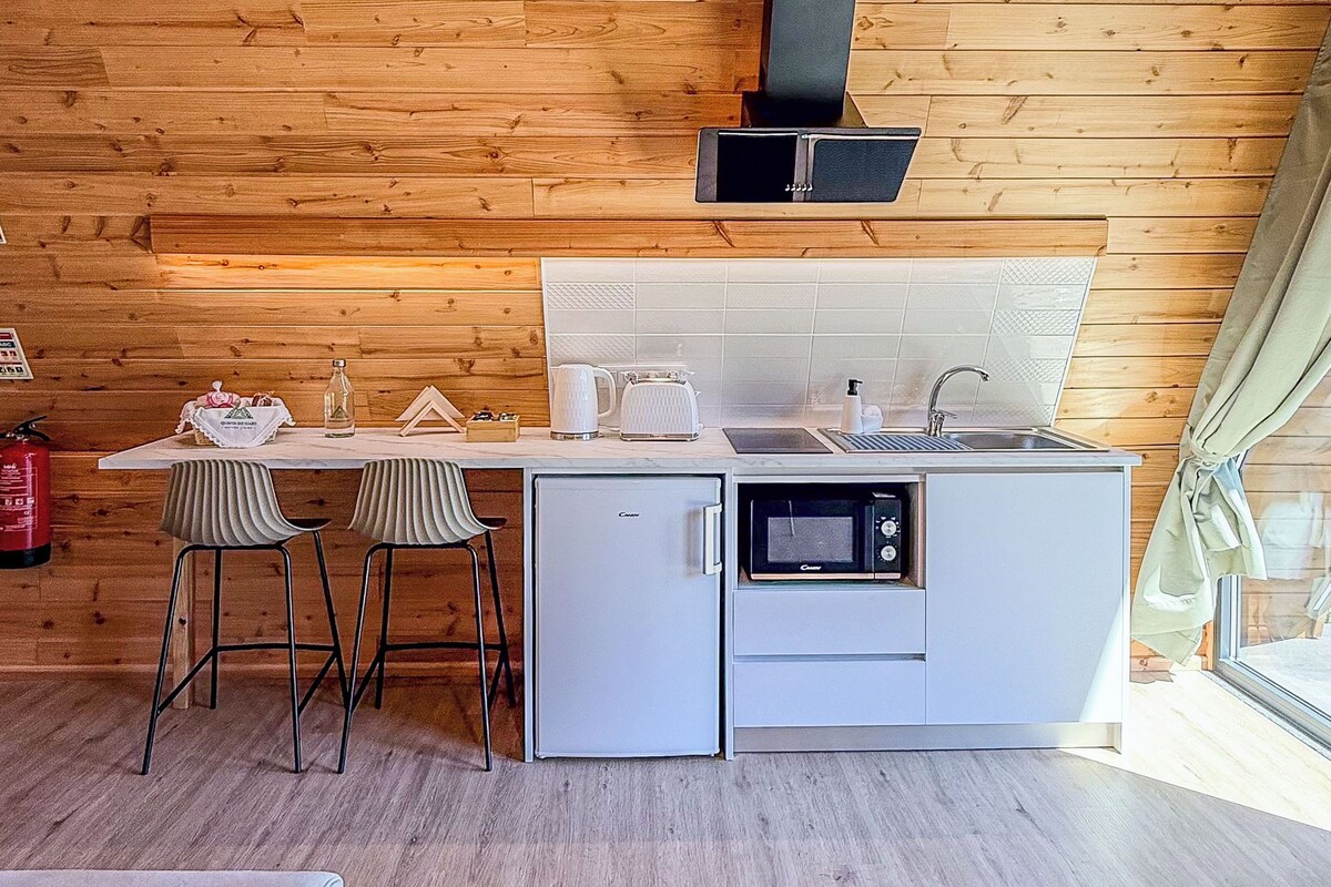 A cozy cabin-style room with a wooden ceiling, a modern kitchen with a built-in oven, and a dining area with a table and chairs.