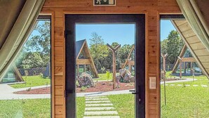 A wooden interior with a large open door leading to an outdoor area with modern buildings and a clear sky.