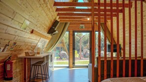 A wooden cabin interior with a kitchen area, a dining space, and a bedroom.
