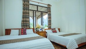 A hotel room with two beds, wooden flooring, and a large window with curtains. - Phong Nha Homie Home (Phong Nha)