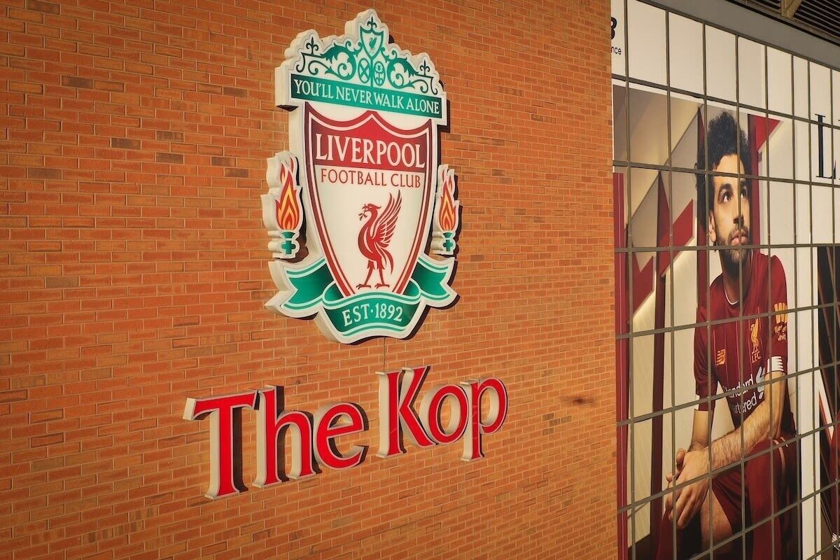 Un muro in mattoni con il logo del Liverpool Football Club e il testo 'The Kop'.