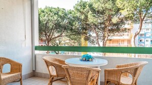 Ein Balkon mit Korbmöbeln und Blick auf Bäume und Gebäude.