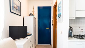 A compact room with a television, a blue door, and a kitchen area with a gas stove.