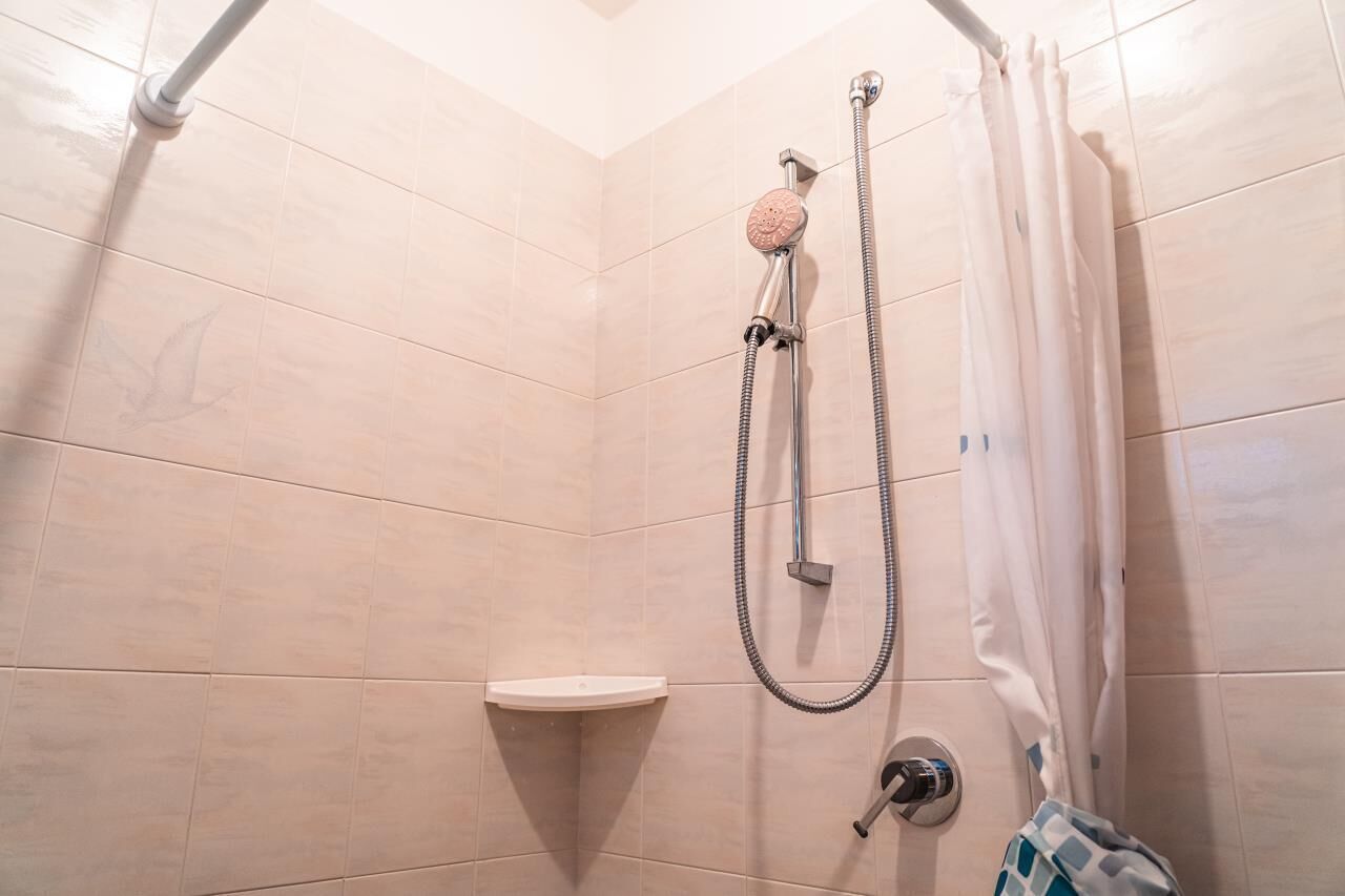 Ducha con cabezal de ducha de mano, grifo empotrado y cortina de ducha.