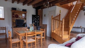 Un salon chaleureux avec une table à manger en bois, des chaises, un canapé et un escalier en bois.
