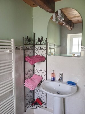 Ein Badezimmer mit einem weißen Waschbecken, einem Spiegel, einem Handtuchhalter mit rosa Handtüchern und einer Heizung.