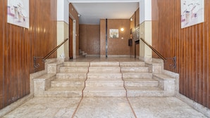 Una escalera de mármol conduce a una habitación con paneles de madera y obras de arte en las paredes.