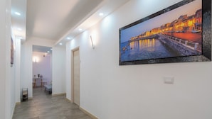 Un pasillo con un cuadro enmarcado que muestra una vista del frente marítimo, iluminación empotrada y una puerta que da a otra habitación.
