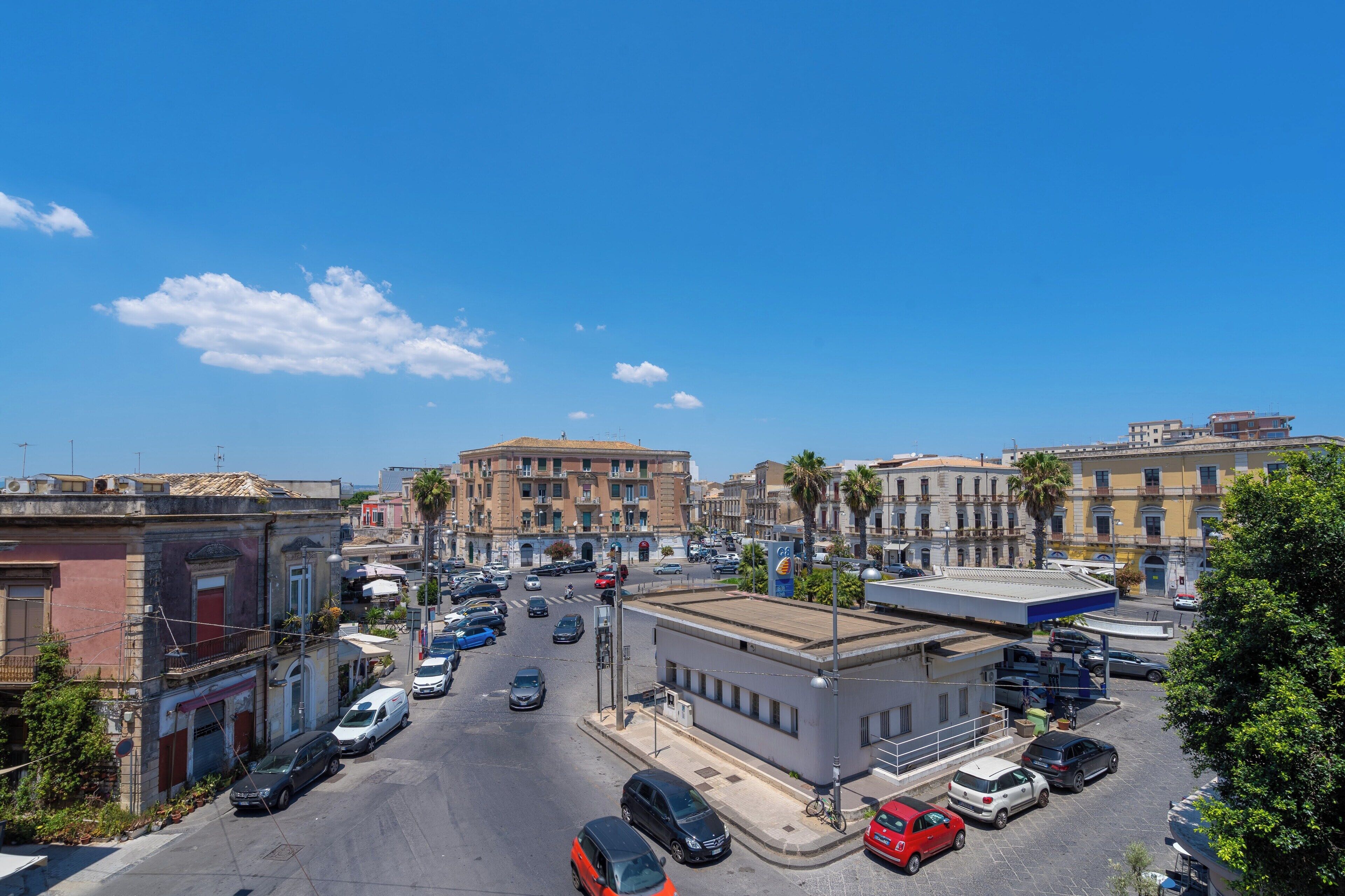 A busy urban street with buildings, cars, and a clear blue sky.