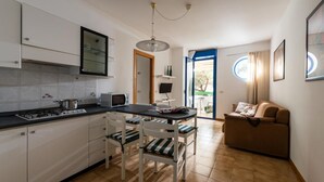 Una cocina compacta con armarios blancos, una estufa a gas y un comedor con mesa y sillas.