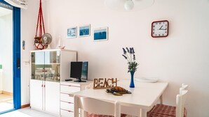 A room with a white table, chairs, a clock, a turtle figurine, and a 'BEACH' sign. - Residence Vera Cruz two-room apartment B4* for 4 persons with sea view (Bibione)