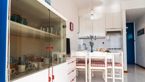 A modern kitchen with white cabinets, a dining table with chairs, and a hanging light fixture. - Residence Vera Cruz two-room apartment B4* for 4 persons with sea view (Bibione)