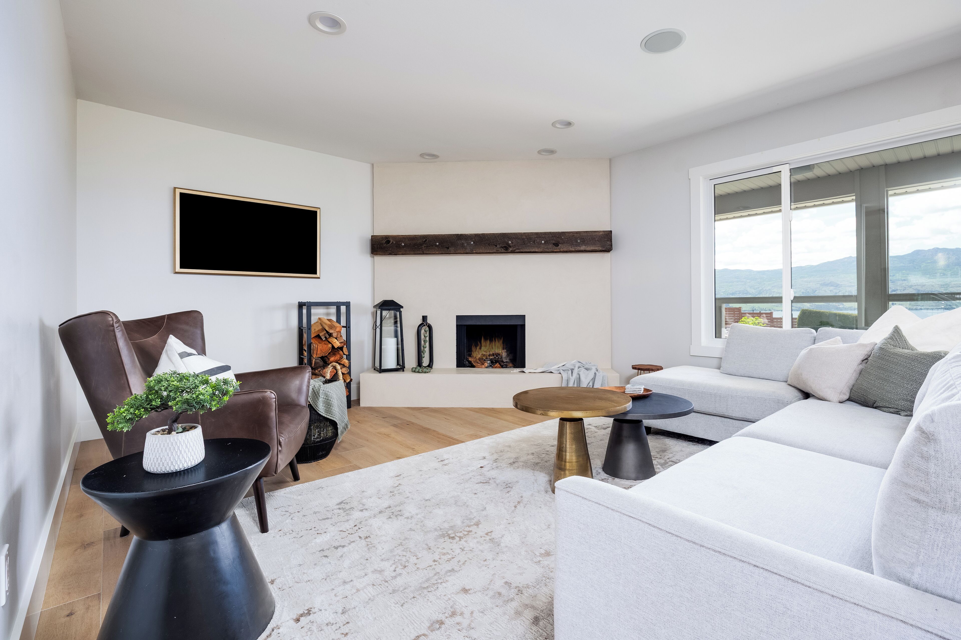 Een moderne woonkamer met een open haard, een groot raam en uitzicht op de omgeving.