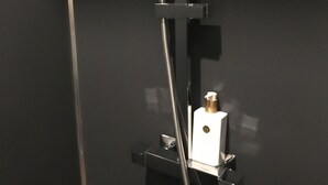 Un mur noir avec une prise électrique blanche et un câble noir branché.