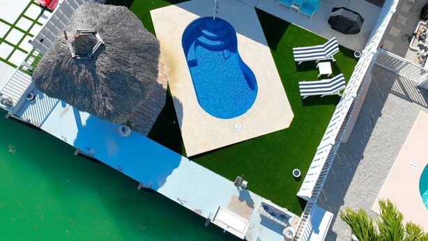 An aerial view of a resort with a pool, lounge chairs, and a thatched-roof structure. - H's Hideaway - Key Colony Beach (Marathon)