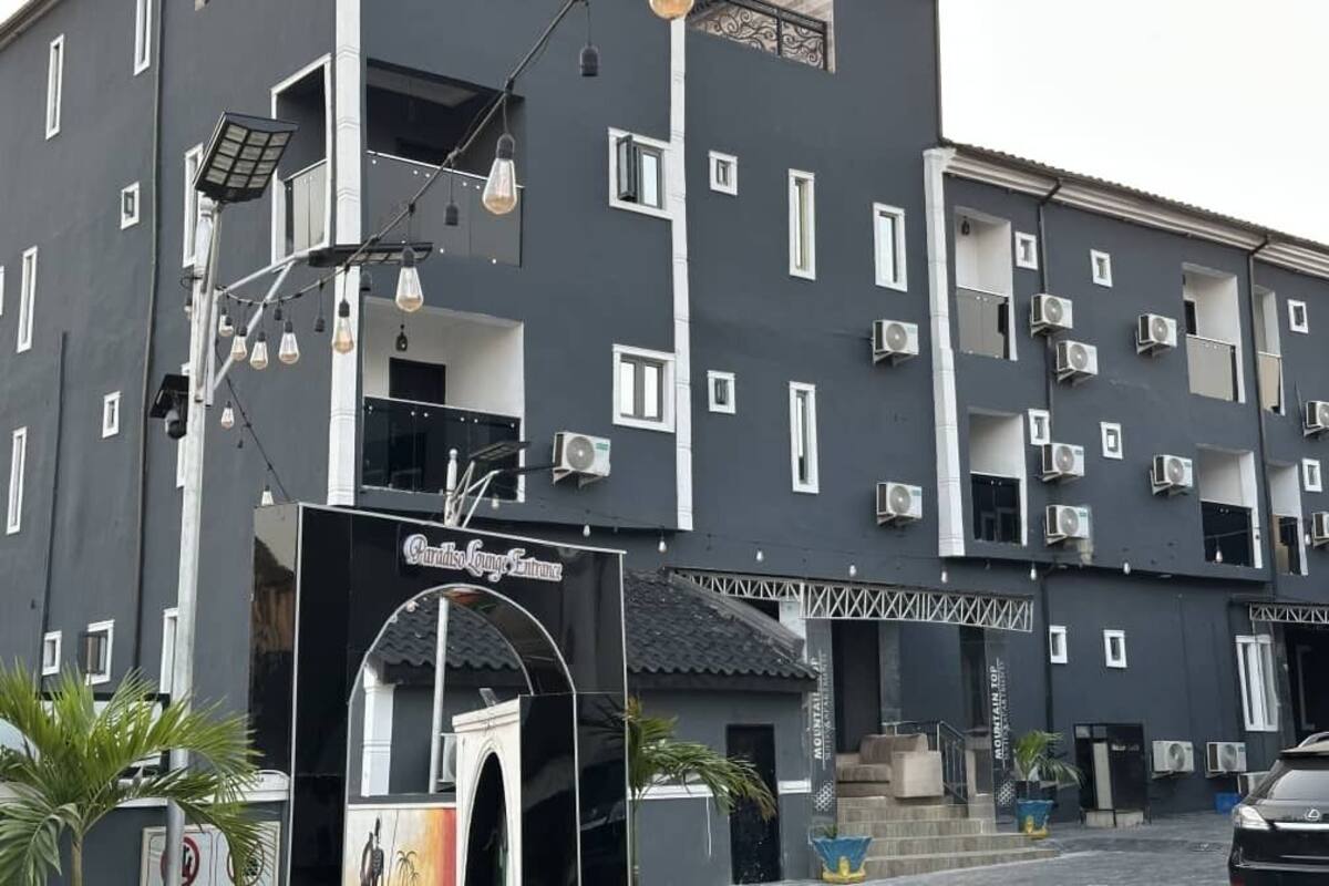 A multi-story building with a dark facade, multiple air conditioning units, and a sign indicating a lounge entrance.