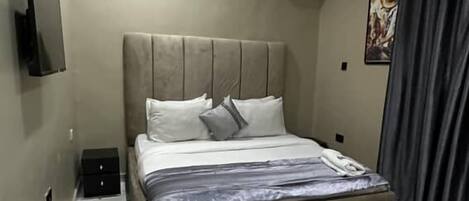 Une chambre à coucher avec un lit, un appareil de climatisation, une télévision et un sol en marbre.