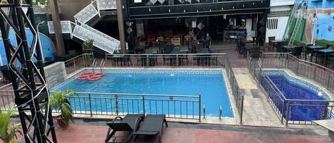 Un área de piscina con dos piscinas separadas, zona de bar y asientos al aire libre.