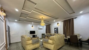 A spacious living room with a sofa set, a dining table with chairs, and a chandelier. - mountaintop suite and apartment (Lagos)