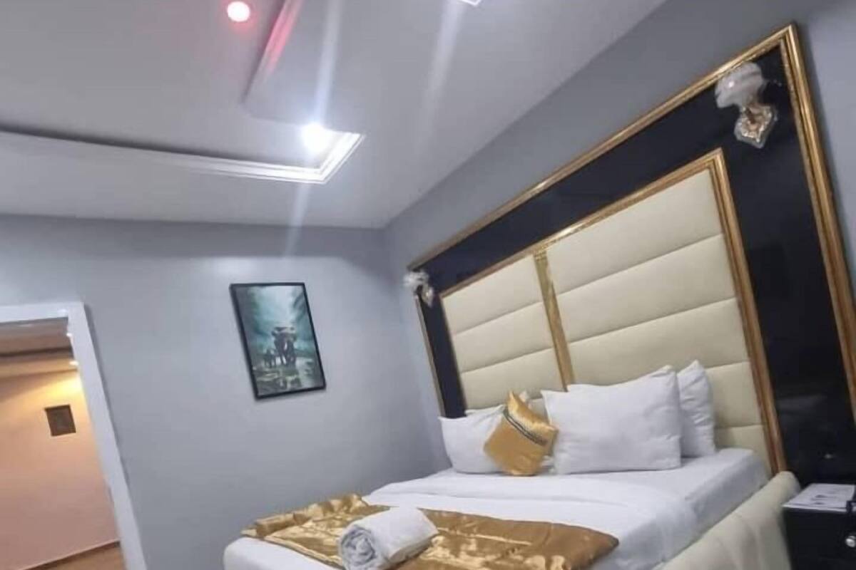 A modern bedroom with a large bed, a headboard, and a bedside table.