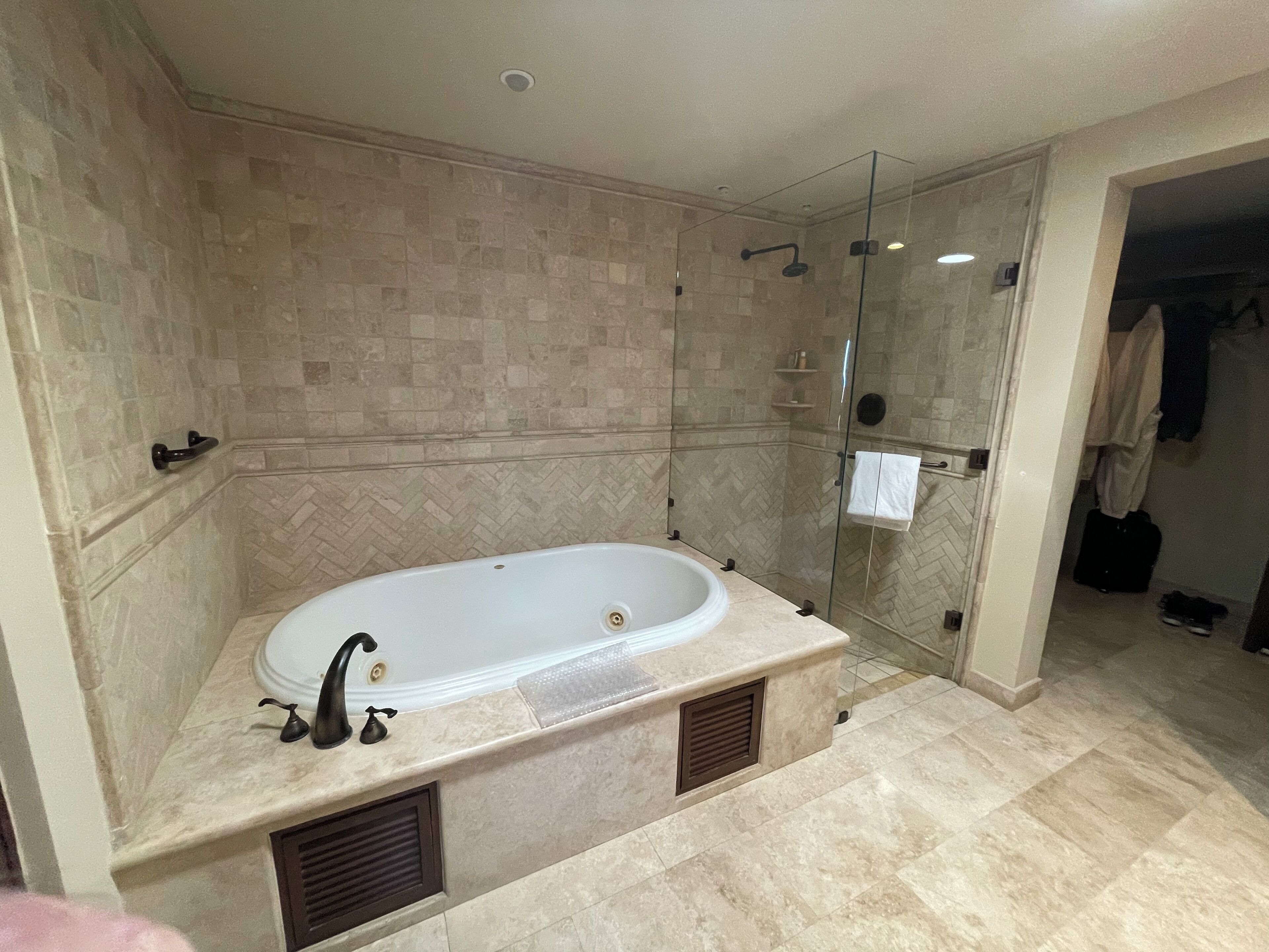 Ein modernes Badezimmer mit einer freistehenden Badewanne, einer Duschkabine aus Glas und einem Boden mit Marmorfliesen.