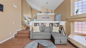 A spacious living room with a sectional sofa, a round coffee table, and a staircase leading to an upper level. - Prime Glendale Location 8-Mins From Westgate Entertainment! (Glendale)