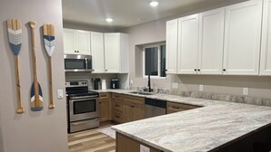 A modern kitchen with white cabinets, a stainless steel oven, a microwave, and a coffee maker. - Scenic lakeside retreat- 5 minute walk to Palisade State Park and Golf Course (Sterling)