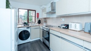 A modern kitchen with a washing machine, oven, and toaster. - Open Mind Property - 1 Bed Flat with 3 Double Beds (Portsmouth)