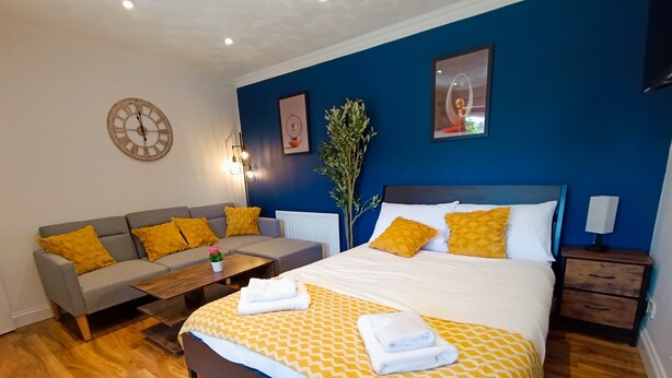 A modern hotel room with a bed, sofa, and nightstands. - Open Mind Property - 1 Bed Flat with 3 Double Beds (Portsmouth)