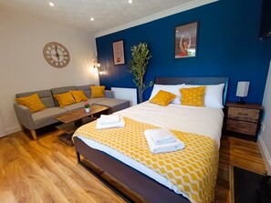 A modern hotel room with a bed, sofa, and nightstands. - Open Mind Property - 1 Bed Flat with 3 Double Beds (Portsmouth)