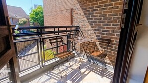 A balcony with a metal railing, a small table, and a chair. - Open Mind Property - 1 Bed Flat with 3 Double Beds (Portsmouth)