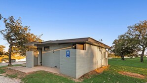 A small, single-story building with a flat roof, a door, and a blue sign indicating a men's restroom. - Lakefront RV spot- Peaceful & breathtaking views, ideal for relax and recharge! (Madill)