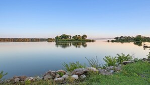 A calm lake with a dock, surrounded by rocky shores and trees.