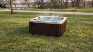 A hot tub in a grassy park area with trees and a path in the background.