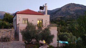 A modern two-story house with a red-tiled roof, stone walls, and a pool. -  Villa Kastania – Cretan Nature Retreat (Melidoni Chania)