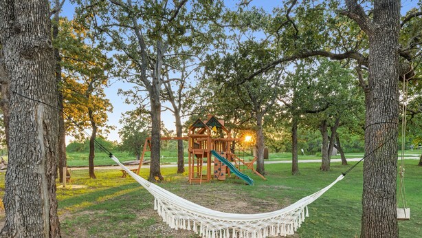 A hammock in a park with a playground structure in the background. - Lakefront RV spot- Peaceful & breathtaking views, ideal for relax and recharge! (Madill)