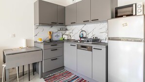 A compact kitchen with grey cabinets, a microwave, a dishwasher, and a clock on the wall. - Modern Studio - AC - 2P - Cannes (Cannes)