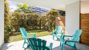A patio with two chairs and a table, a wooden fence, and a view of a building and trees. - Modern Studio - AC - 2P - Cannes (Cannes)