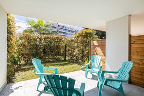 A patio with two chairs and a table, a wooden fence, and a view of a building and trees. - Modern Studio - AC - 2P - Cannes (Cannes)