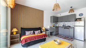 A modern bedroom with a bed, bedside tables, a desk, and a kitchen area with cabinets and appliances. - Modern Studio - AC - 2P - Cannes (Cannes)