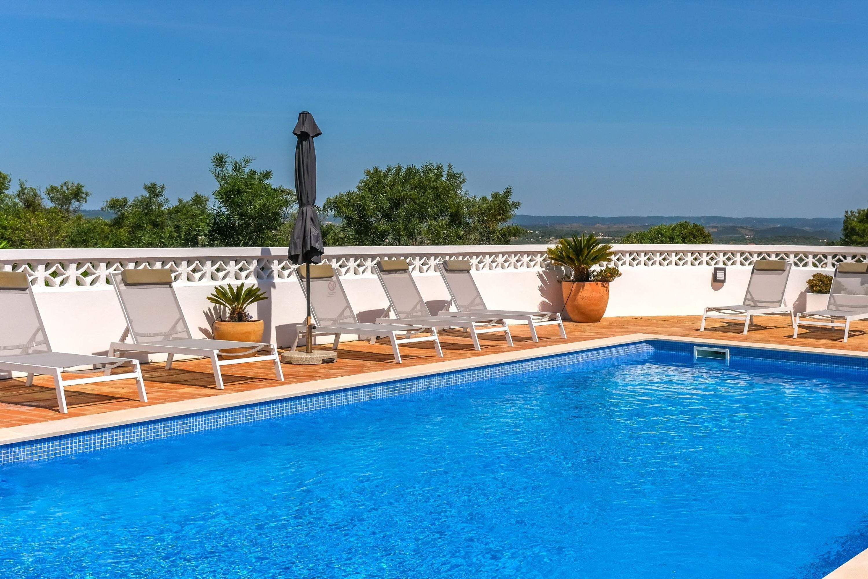 Zona de piscina con sillones de descanso y vistas del paisaje.
