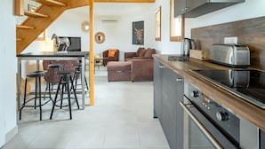 Une cuisine moderne avec un escalier en bois, un coin repas avec des tabourets de bar et un salon avec un canapé.