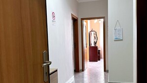 Un pasillo con una puerta de madera, un perchero y un letrero de bienvenida.