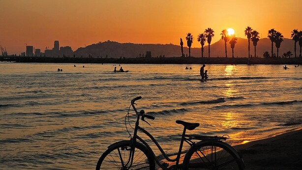 Una vista del atardecer con una bicicleta apoyada en la playa.