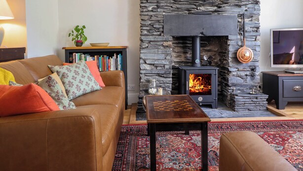 Un salon chaleureux avec une cheminée en pierre, un canapé en cuir, une table basse et une bibliothèque.