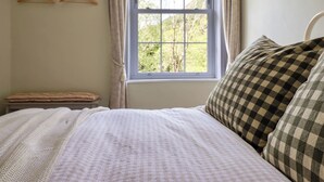 Une chambre à coucher avec un lit, une fenêtre, une étagère avec un vase et un cadre photo.